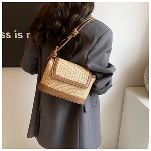 Détail du sac bandoulière en paille et cuir avec bandoulière nouée porté par un mannequin