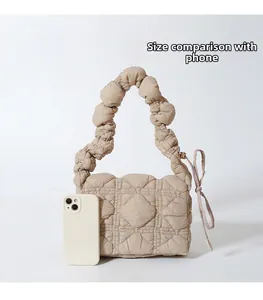Detailed size comparison of mini quilted nylon handbag next to a smartphone