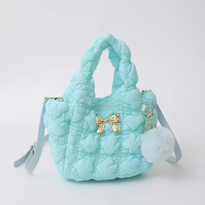Détail du sac matelassé bleu clair en nylon avec nœud doré et breloque en peluche