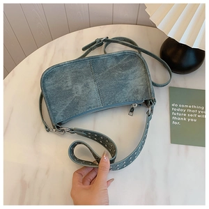 Gros plan du sac sous le bras en denim bleu avec des clous argentés sur marbre