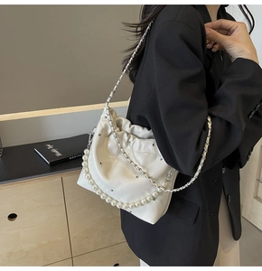 Detail of white quilted handbag featuring silver studs and elegant pearl handle strap