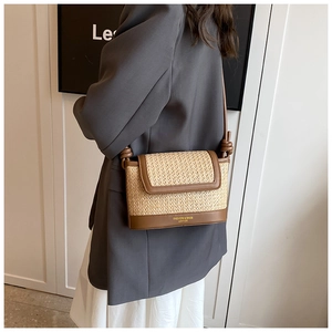 Détail du sac bandoulière en paille tressée et cuir marron avec logo doré