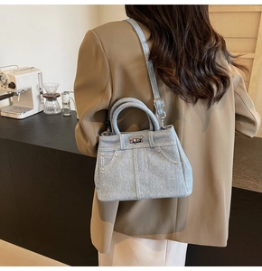 Détail du sac bandoulière en denim bleu clair avec clous et fermoir rotatif