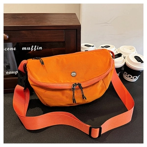 Vibrant orange nylon crescent crossbody bag with adjustable strap in casual urban setting