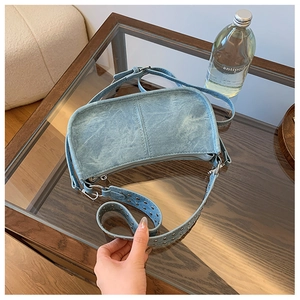 Détails des clous argentés sur la bandoulière en denim bleu clair du sac vintage