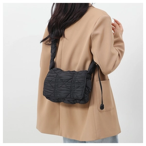 Detail view of black quilted nylon crossbody bag with side drawstring on a model
