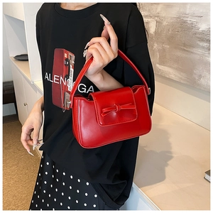 Close-up of vibrant red PU leather handbag featuring a stylish bow and metal buckle