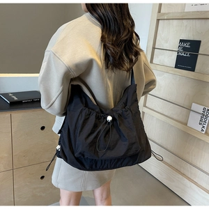 Detail view of large black nylon crossbody bag with drawstring closure and white buckle