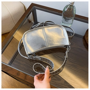 Détail du sac à bandoulière argenté métallisé avec rivets et finition miroir brillante