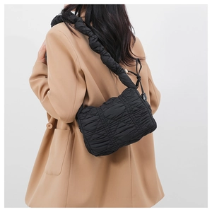Detail of a black quilted nylon shoulder bag with a unique pleated strap and airy texture