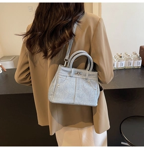 Détail du sac bandoulière en denim bleu clair avec clous et design de poche jean