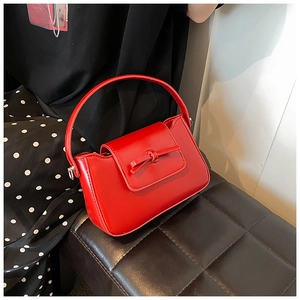 Detail of red PU leather handbag with decorative bow on a textured background
