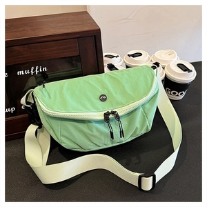 Light green washed fabric crossbody bag with dual zippers and adjustable wide strap