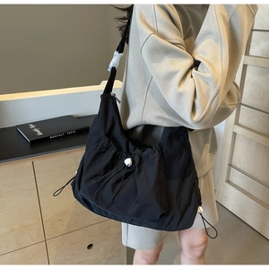 Detailed close-up of black nylon crossbody bag featuring drawstring and white buckle