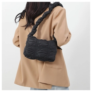 Rear view of a model wearing a black quilted nylon shoulder bag with a ruched strap