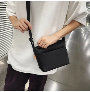 Detail showing the matte fabric texture, side orange label, and adjustable strap on the bag