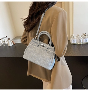Détail d'un sac à bandoulière en denim bleu clair avec fermoir argenté porté par un mannequin