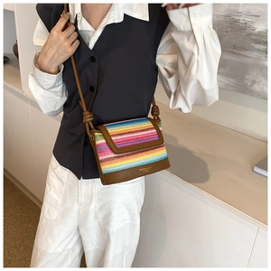 Détail du sac bandoulière en paille arc-en-ciel avec base en cuir marron et lanière