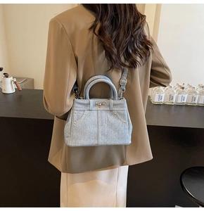 Détail du sac à bandoulière en denim bleu clair avec coutures contrastées et rivets