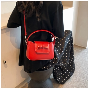 Detail of red PU leather handbag with a bow decoration and adjustable shoulder strap