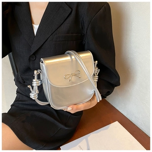 Detailed view of silver PU leather crossbody bag with knot strap and bow hardware