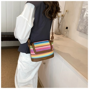 Détail du sac bandoulière tissé arc-en-ciel avec bordure en cuir brun et logo doré
