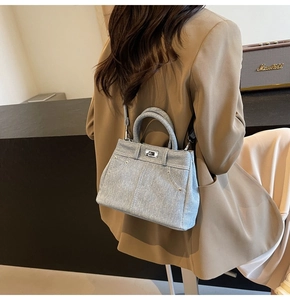 Détail du sac à main en denim bleu clair avec fermoir rotatif argenté et surpiqûres