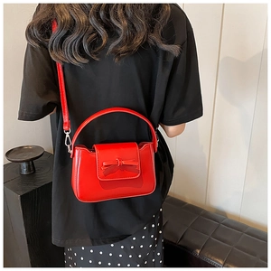 Detail view of the red glossy patent leather handbag with a chic bow decoration on the back