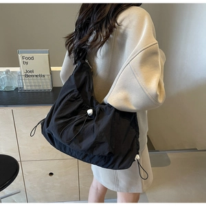 Close-up of black nylon drawstring tote bag with white buckle detail on model