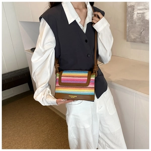 Détail d'un sac bandoulière en paille tissée colorée avec garniture en cuir brun