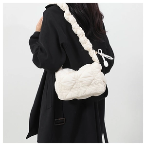 White quilted nylon crossbody bag with pleated shoulder strap styled on a black coat