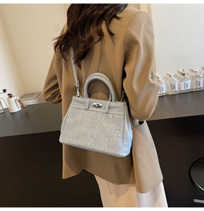 Détail d'un sac à bandoulière en jean bleu clair style Kelly porté par un mannequin