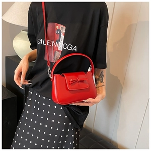 Detail of red semi-circular PU crossbody bag with bow accent and top handle