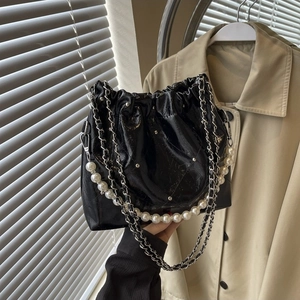 Glossy black PU cloud bag with silver chain and white pearl strap held by hand