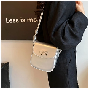 Detail of silver metallic PU crossbody bag with metal bow and knotted strap
