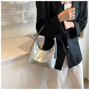 Sac hobo argenté avec motif de losanges matelassés et rivets porté par un mannequin