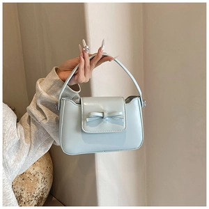 Detail of light blue PU leather handbag featuring a stylish 3D bow decoration and handle
