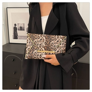 Fashionable leopard print clutch bag with gold trim held by model in black blazer