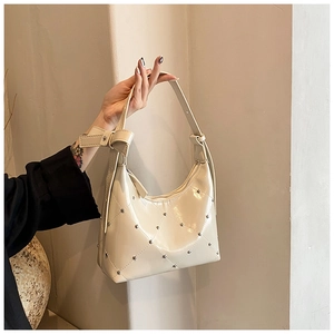 Détail du sac sous le bras en similicuir crème avec motif matelassé et clous métalliques