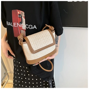 Détail d'un sac bandoulière en paille et cuir avec bandoulière à nœud et logo doré
