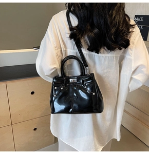 Modèle portant un sac à bandoulière en PU noir brillant avec détails argentés sur une chemise