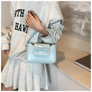 Detail of light blue PU leather crossbody bag featuring a decorative bow on the front flap