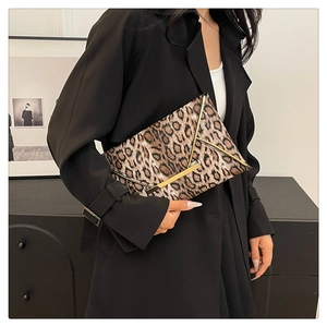 Close-up of leopard print envelope clutch bag with gold metallic trim held by a model