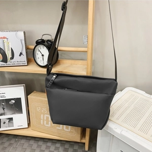 Minimalist grey nylon crossbody bag for women hanging in a cozy home setting