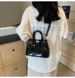 Détail d'un sac à main noir en similicuir brillant avec fermoir rotatif argenté et rivets