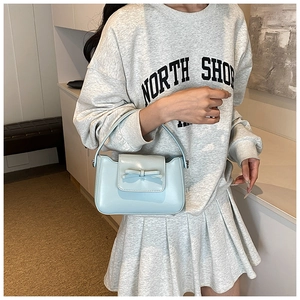 Detail of light blue PU leather crossbody bag featuring a decorative bow and top handle
