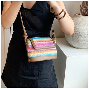 Détail du sac à bandoulière en paille tressée arc-en-ciel avec lanière en cuir sur modèle