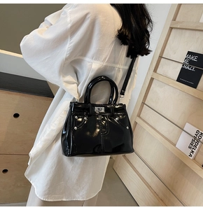 Détail du sac à bandoulière en cuir verni noir avec fermoir rotatif argenté et sangle