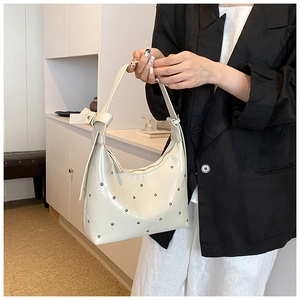 Détail du sac hobo en PU crème avec clous métalliques argentés et anse à nœud élégante