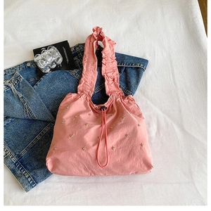 Roze handtas met trekkoord, ruches handvatten en gouden studs op spijkerjasje